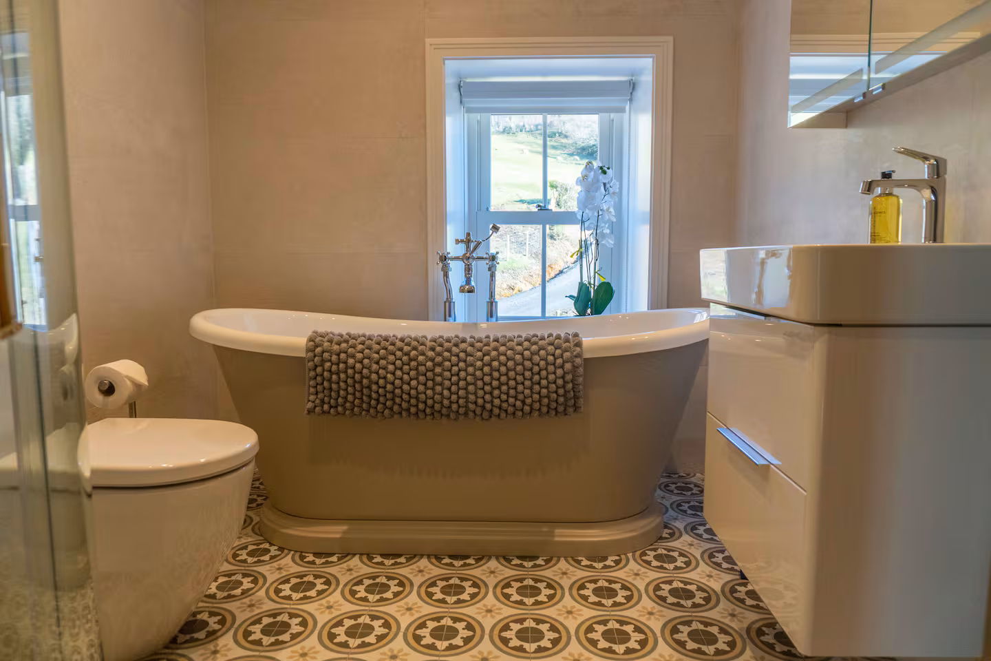 Stone-grey freestanding bath at The Farmhouse with a window onto the valley