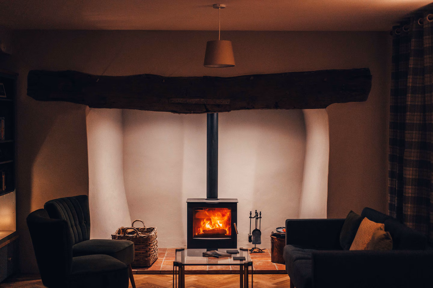 The inglenook fireplace at The Farmhouse, with logs and two armchairs