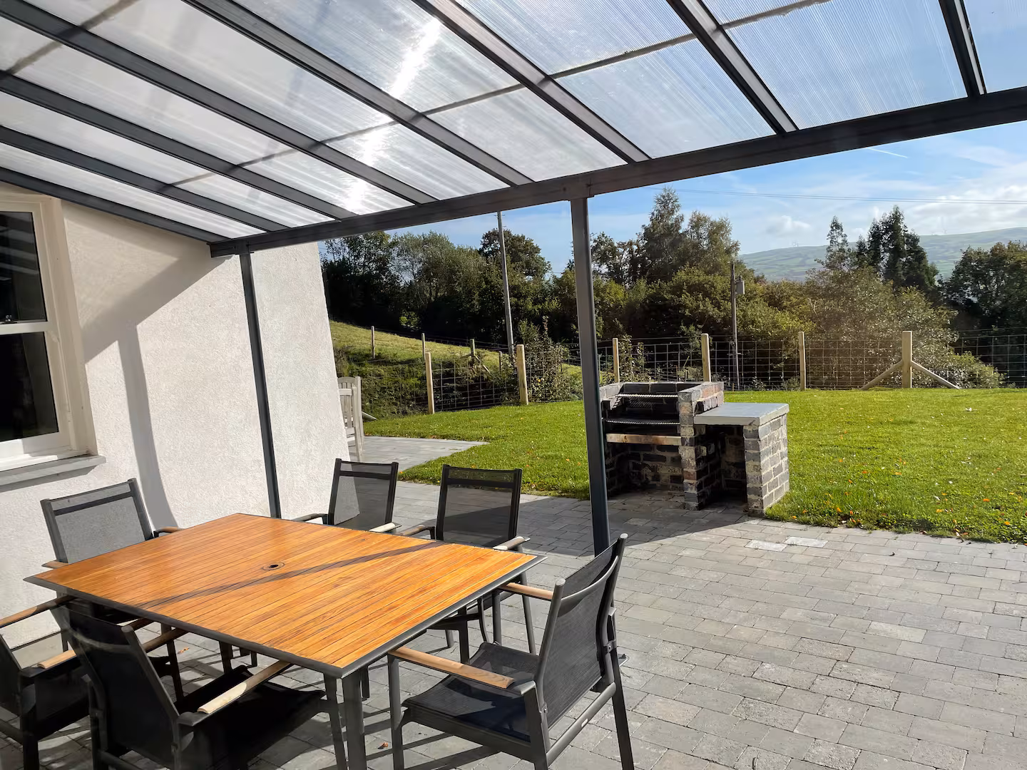 The Farmhouse covered terrace — stone BBQ and teak table, useable in any weather